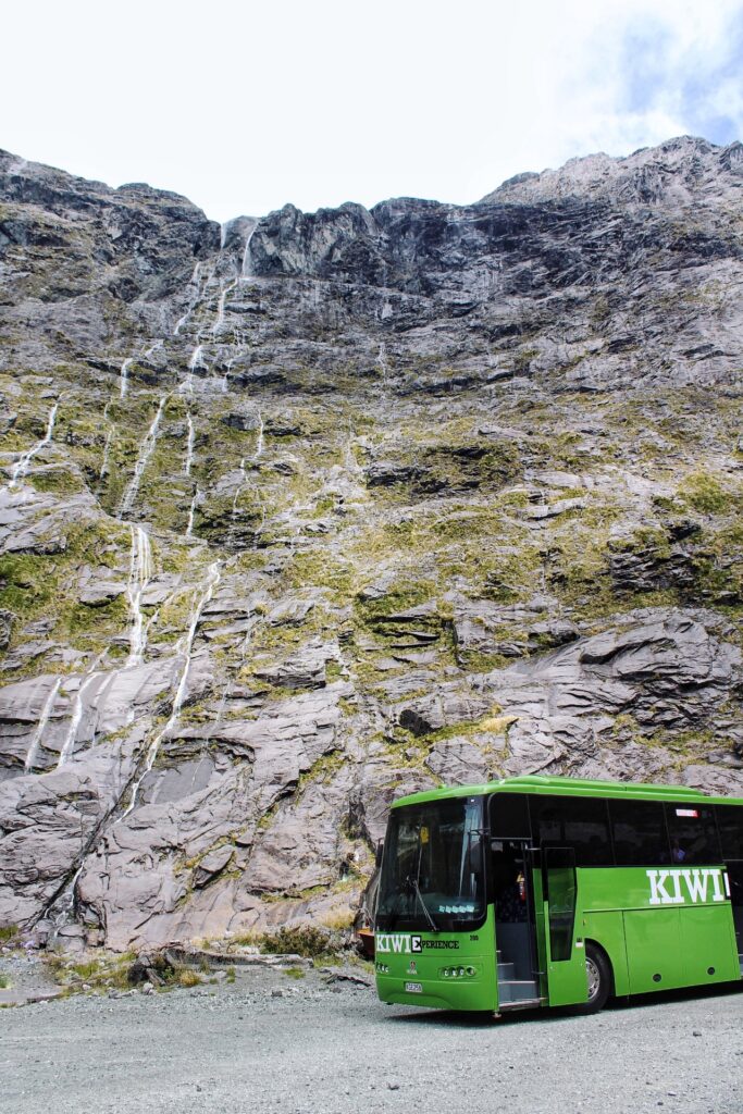 thousand waterfalls, milford sound, new zeaalnd. kiwi experience bus in foreground