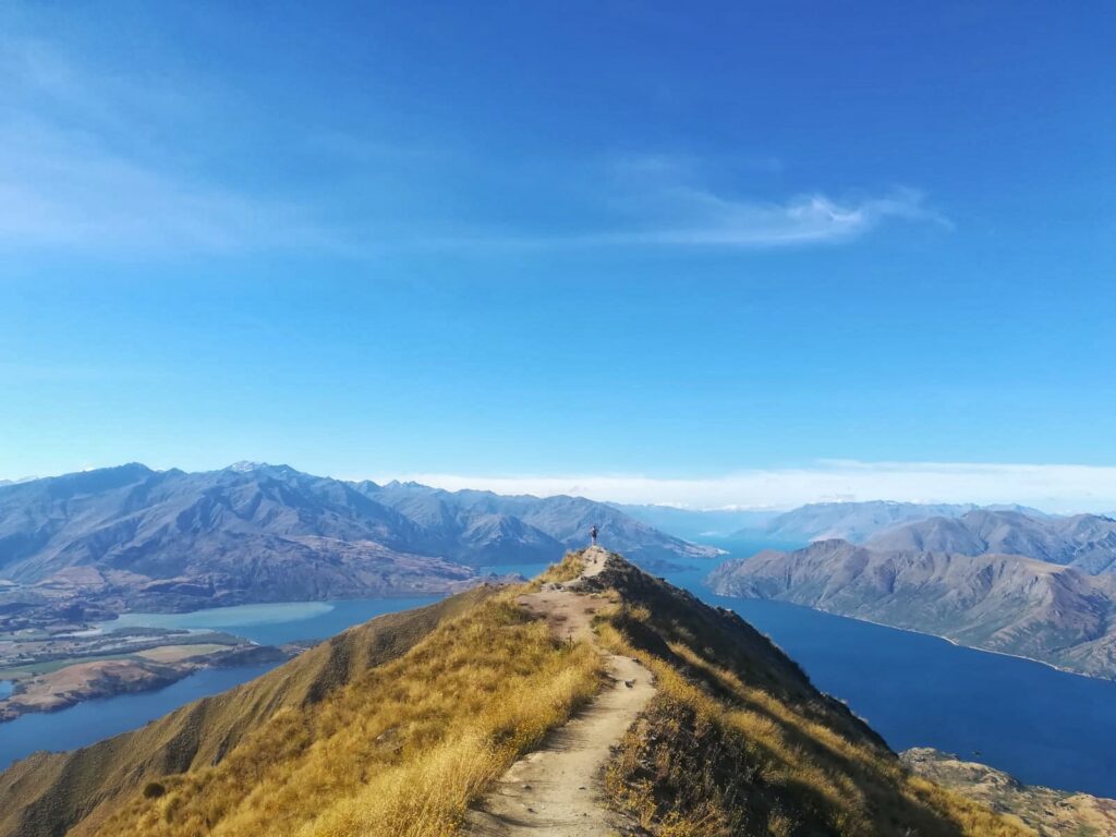 melody standing on roys peak summit, wanaka, new zealand. lake and mountains in background