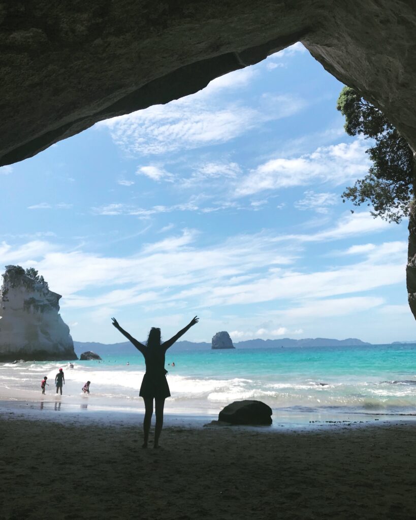 cathedral cove, new zealand. melody standing in the cave entrance with arms outsretched