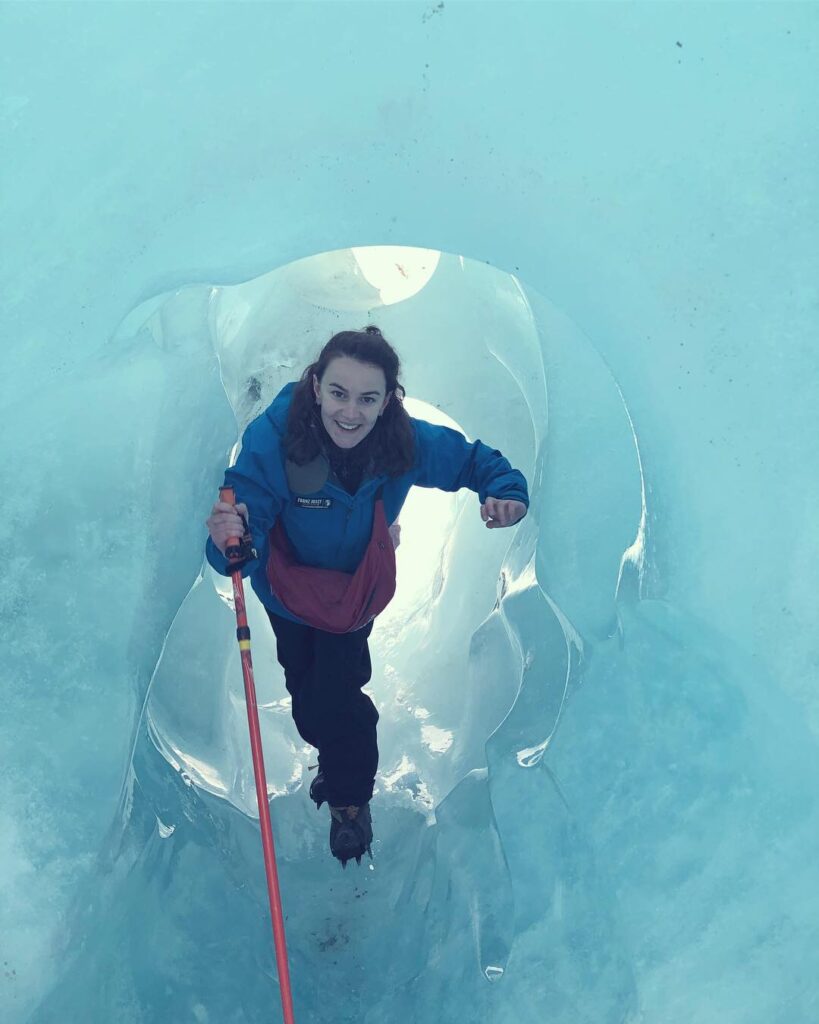 melody standing in ice tunnel on franz josef glacier, new zealand