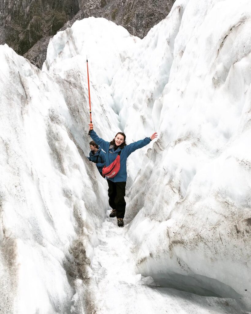 melody posing with arms outstretched on franz josef glacier, new zealand