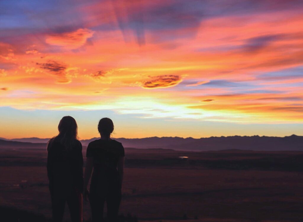 beautiful sunset on mt john, lake tekapo, new zealand. melody and friend standing in foreground