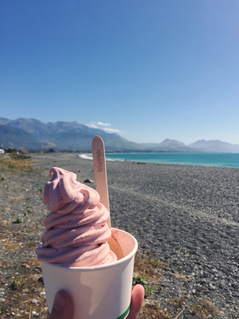 ice cream in front of black sand beach in kaikoura, new zealand