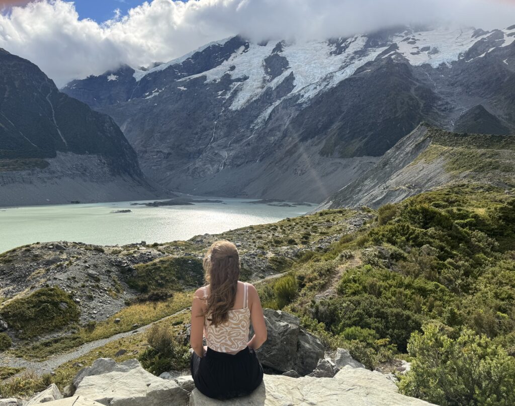 glacial lake and mountains on hooker valley track, new zealand. melody sitting in foreground