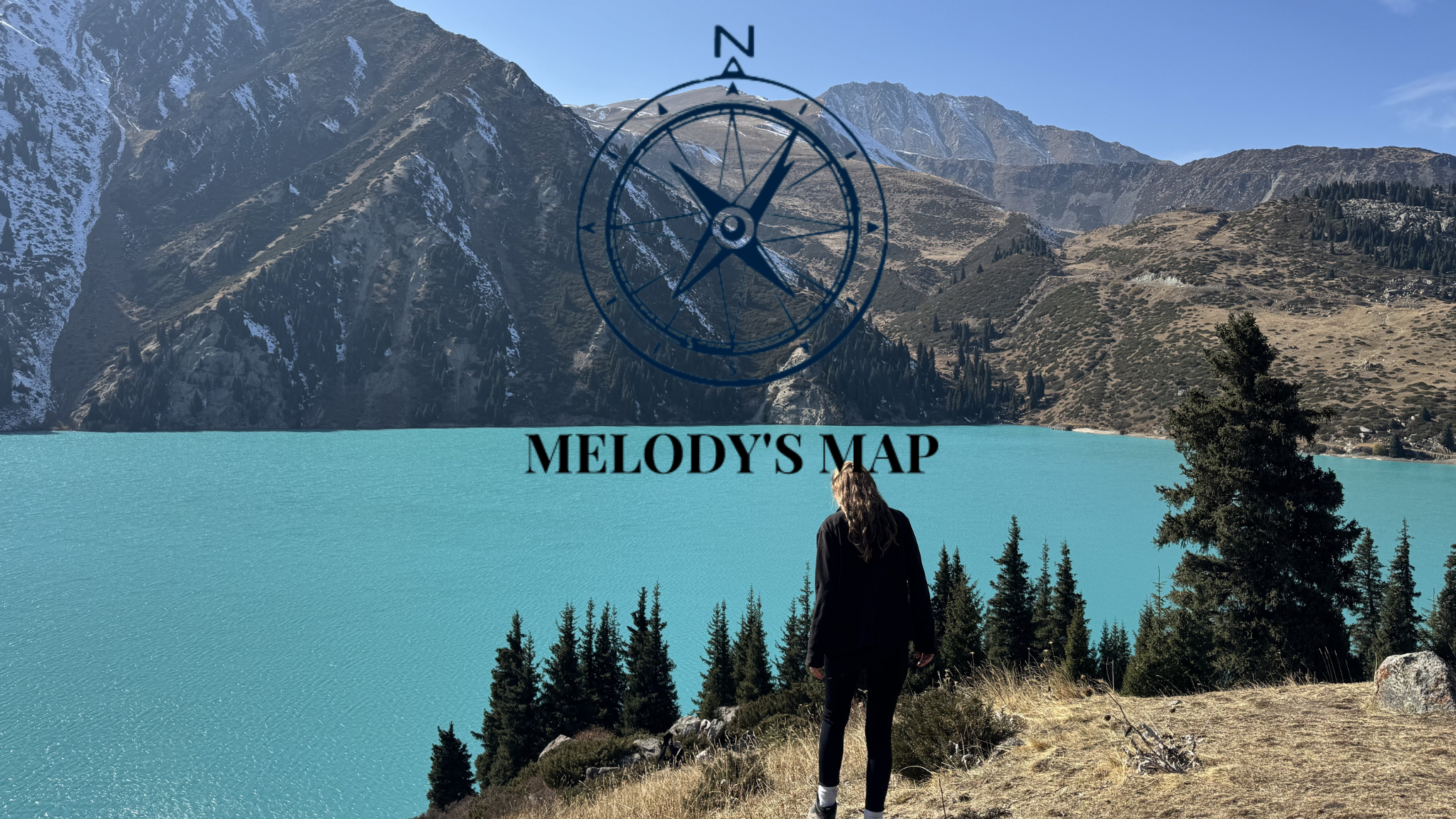 Melody's Map. Melody standing infront of a clear blue glacial lake in kazhakstan with mountains in the backgound