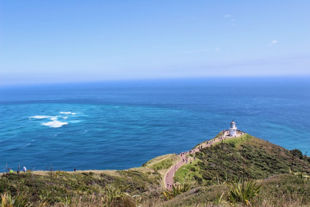 view of cape reinga lighthouse on cliff with ocean in babckground, new zealand. north island hikes in new zealand