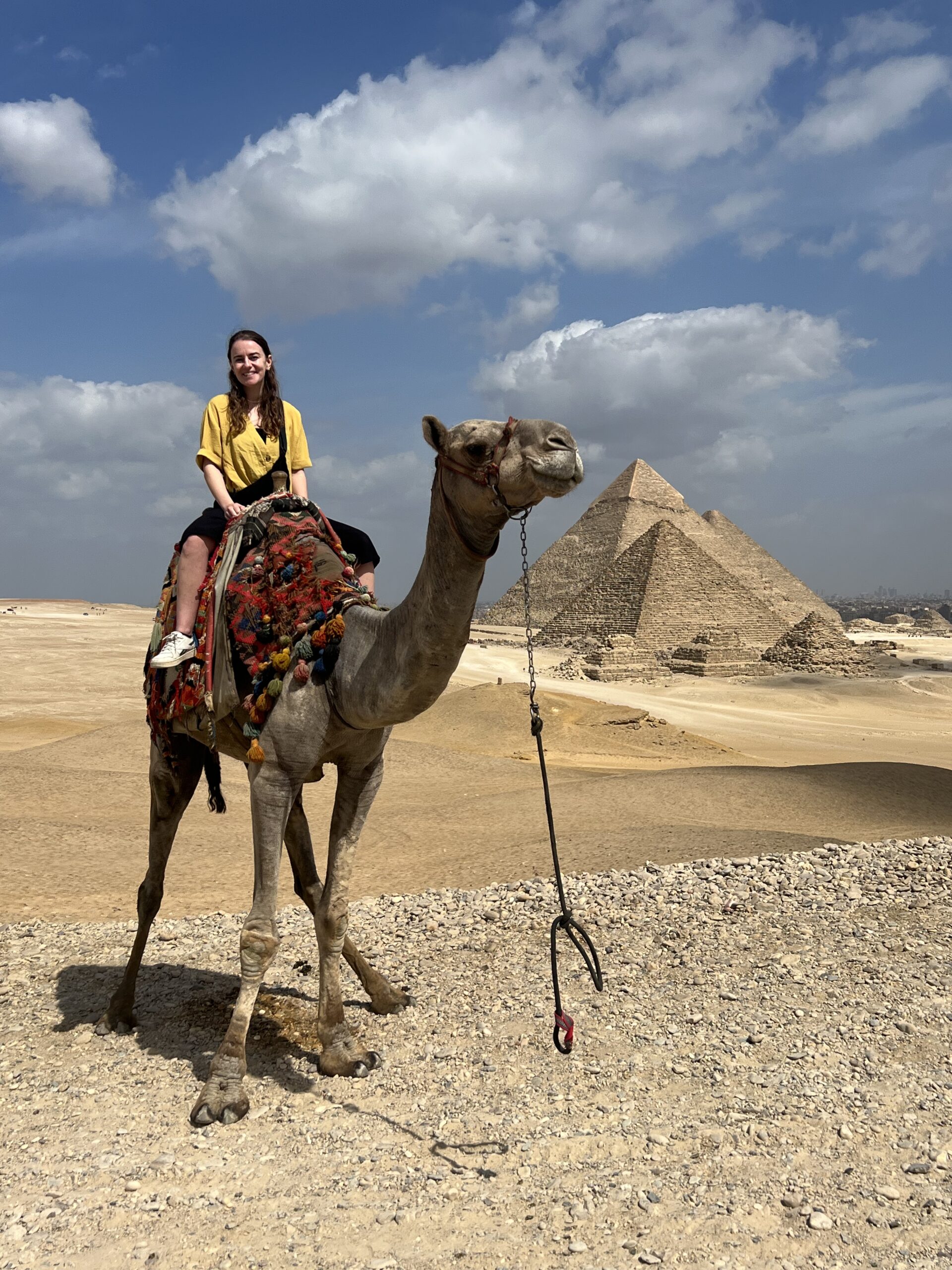 meoldy sitting on camel in front of pyramids of giza, egypt