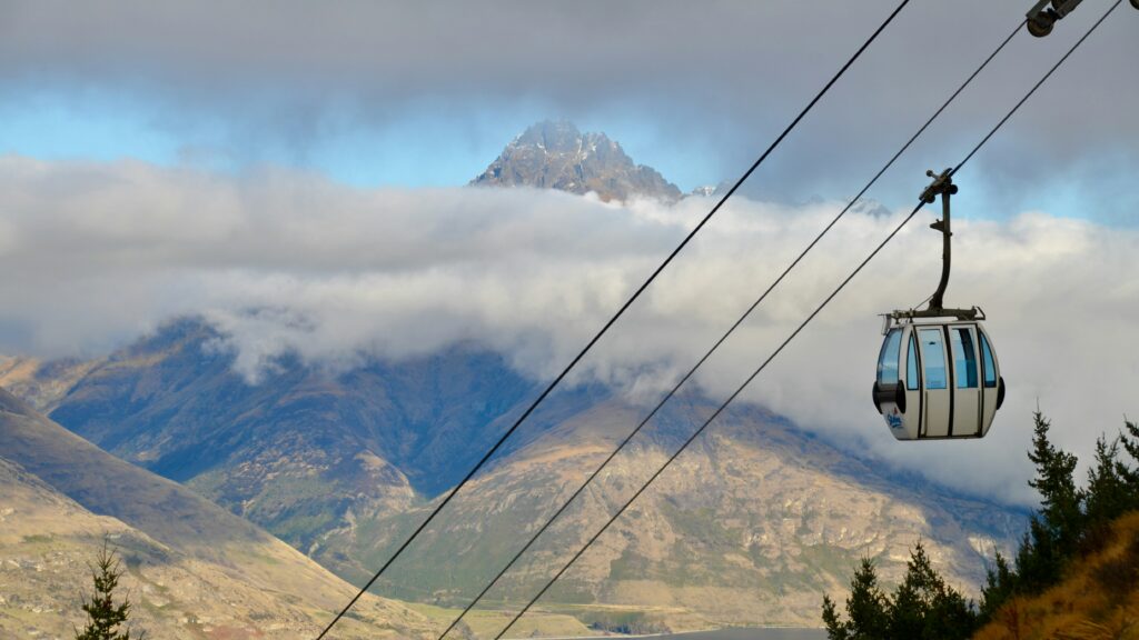 gondola in queenstown, new zealand. mountains and clouds in background.
